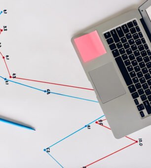 Laptop with financial chart and graph on display on blueprint with graphical statistics